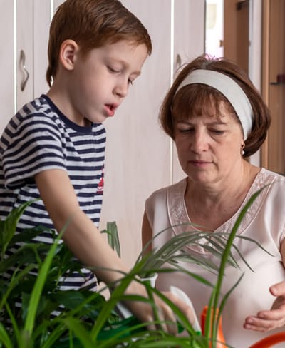 A woman and a child caring for plants indoors.