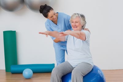 Riverside Manor, nursing home in Ames, IA — Senior resident exercising with a trainer on a stability ball