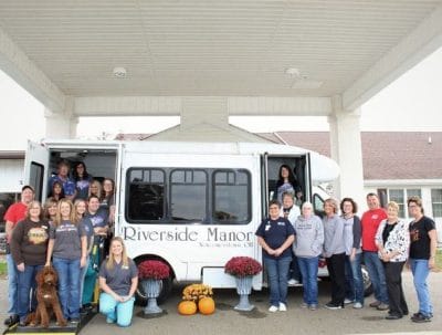 Staff and residents pose by facility vehicle