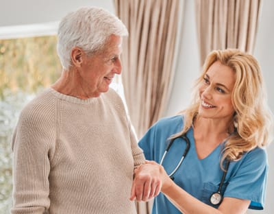 Riverside Manor, nursing home in Ames, IA — Caregiver assisting a senior man with a warm smile