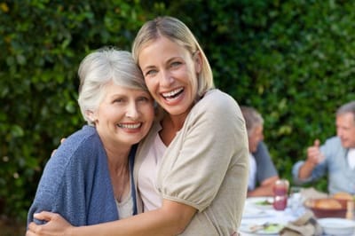 Riverside Manor, nursing home in Ames, IA — Smiling woman embracing older woman in garden setting