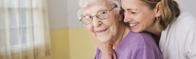 Riverside Manor, nursing home in Ames, IA — Senior woman smiling with caregiver in a bright room
