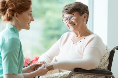 Riverside Manor, nursing home in Ames, IA — Caregiver assisting a senior woman in a wheelchair
