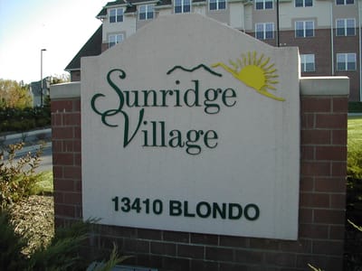 Sign for Sunridge Village facility with mountain and sun design