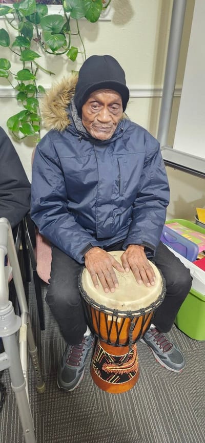 Resident playing a djembe drum in an activity room