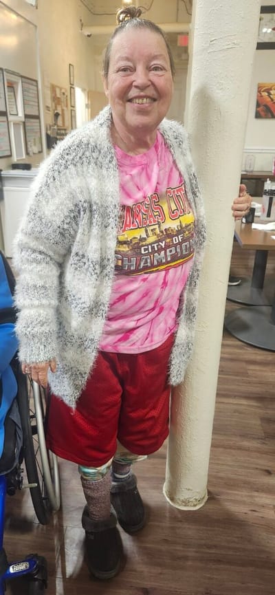 Resident smiling in a vibrant outfit inside the facility