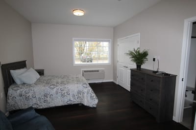 Interior view of a resident's room with a bed and dresser