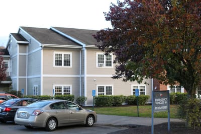 Exterior view of a nursing home building with parked cars