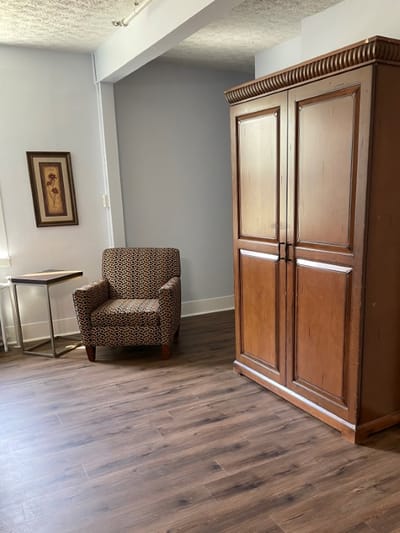 A cozy living area with a chair and an armoire
