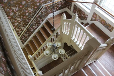 Staircase with floral wallpaper and light fixture