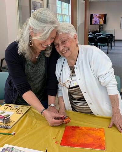 Residents engaging in an art activity with staff member
