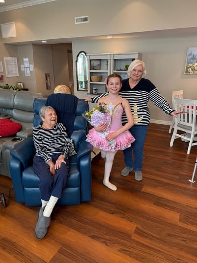 Residents enjoying time with a young dancer in a common area