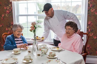 Staff serving dessert to residents in a dining room