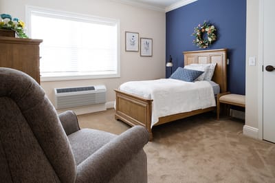 Cozy interior of a resident's room with a bed and chair