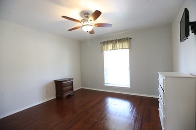 A private room with a wooden dresser and ceiling fan