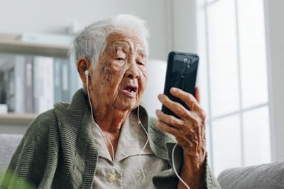 Elderly woman using a smartphone with earbuds