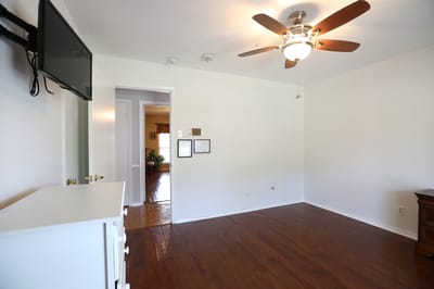 A simple resident room with wooden flooring and ceiling fan