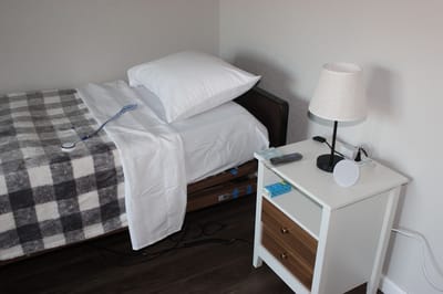A private resident room with a bed and bedside table
