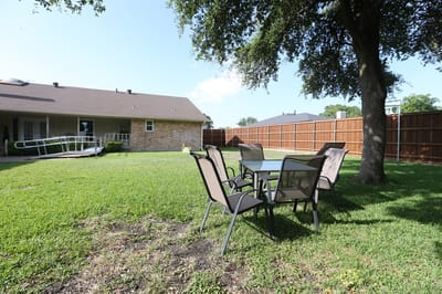 Outdoor seating area with a table and chairs on green grass