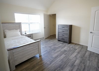 Well-furnished private resident room with a bed and chest of drawers