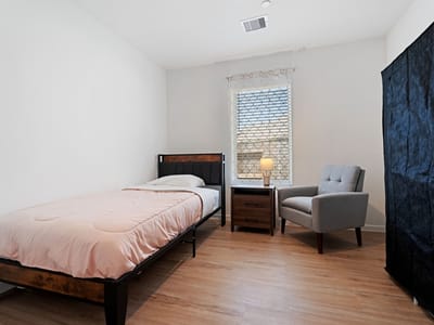 A cozy private resident room with a bed and chair