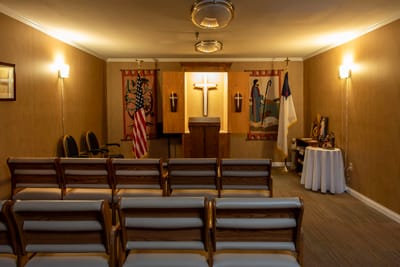 Chapel interior with seating, cross, and flags