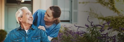 Staff assisting a resident outdoors in a garden.