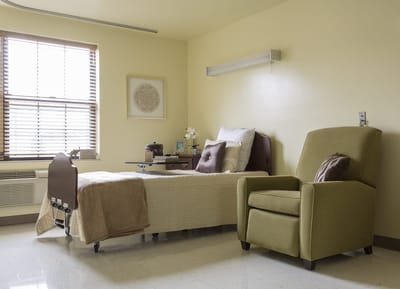 A private resident room with a bed and chair