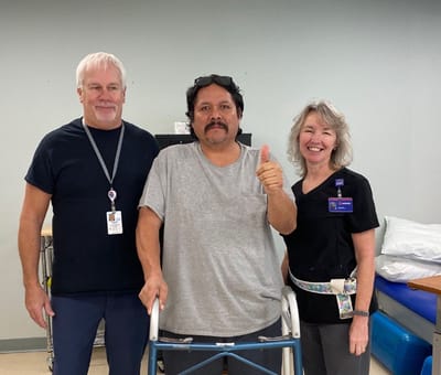 Staff and resident posing together in therapy room