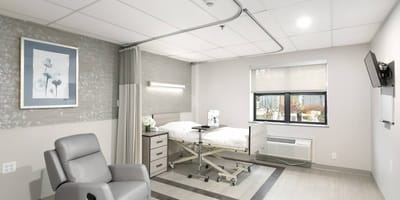 A private resident room with medical equipment and comfortable chair