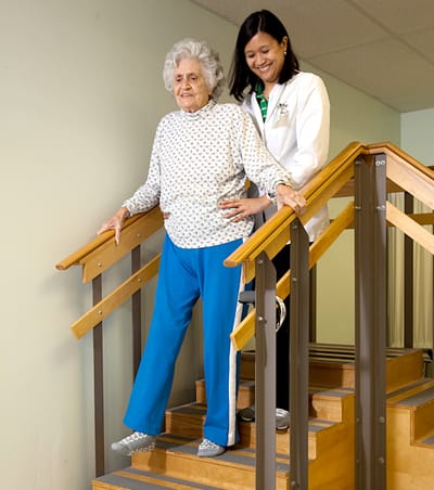 Hunterdon Care Center, Nursing Home in Flemington, NJ — Senior caregiver assisting elderly resident on staircase