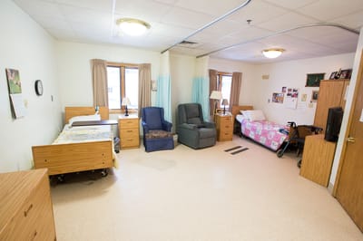 A bright resident room with two beds and seating areas