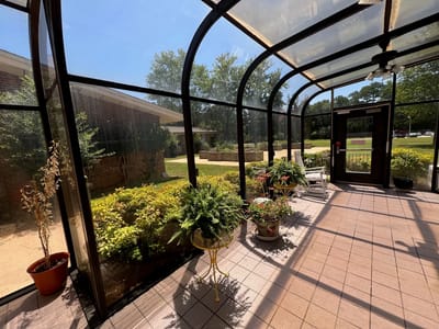 Sunlit entrance with potted plants and seating.