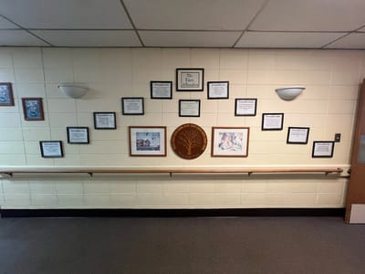 Wall display with framed photos and plaques.
