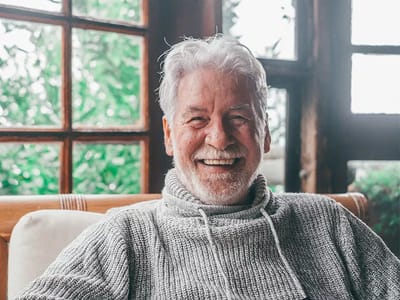 Smiling older man with gray hair in cozy setting.