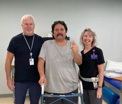 Staff assisting a resident with a walker.