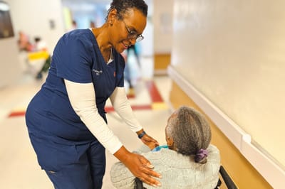 Staff member assisting a resident in a hallway.