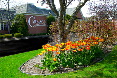 Exterior view of Care-Age facility with flowers
