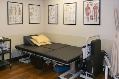 A therapy room with anatomical posters and a treatment table