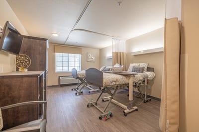 Bright resident room with two beds and TV