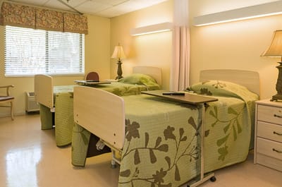 A cozy shared resident room with beds and lamps