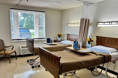 Bright resident room with two beds and flowers