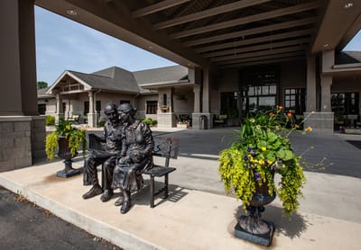 Statue of an elderly couple on a bench outside the facility