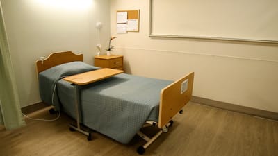 Private resident room with a hospital bed and bedside table