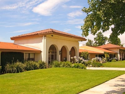 Exterior view of a senior living facility with green lawn