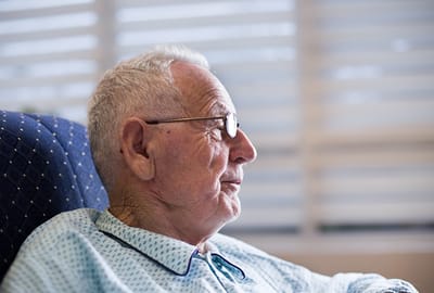 Senior man sitting thoughtfully in a chair.