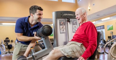 Resident exercising with trainer in gym