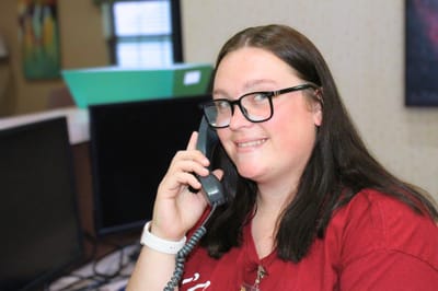 Staff member at a desk using a phone.