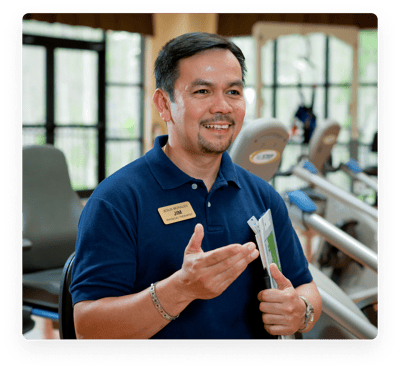 Staff member interacting with residents at a fitness area.