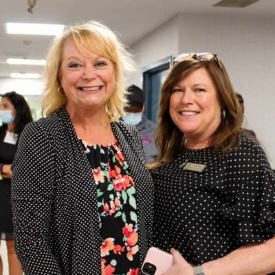 Two staff members smiling in a hallway